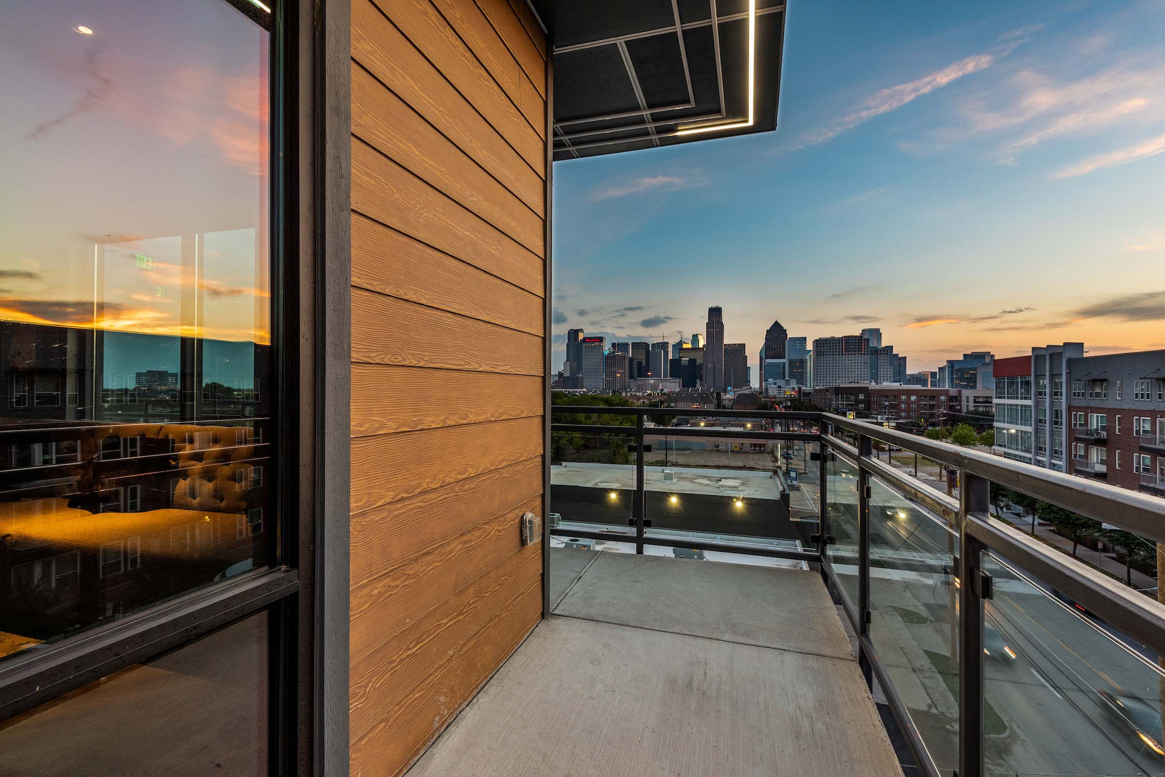Balcony with wood paneling and glass railing overlooking street.