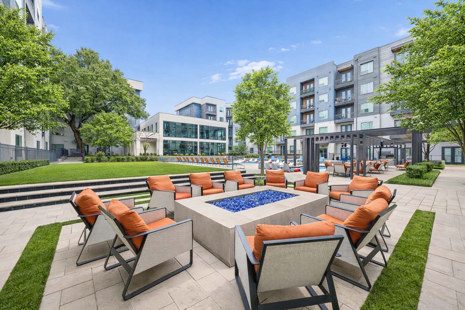 Luxury apartment community outdoor lounge featuring a modern fire pit, resort-style pool, landscaped courtyards, shaded gathering areas, and contemporary seating for residents and guests.